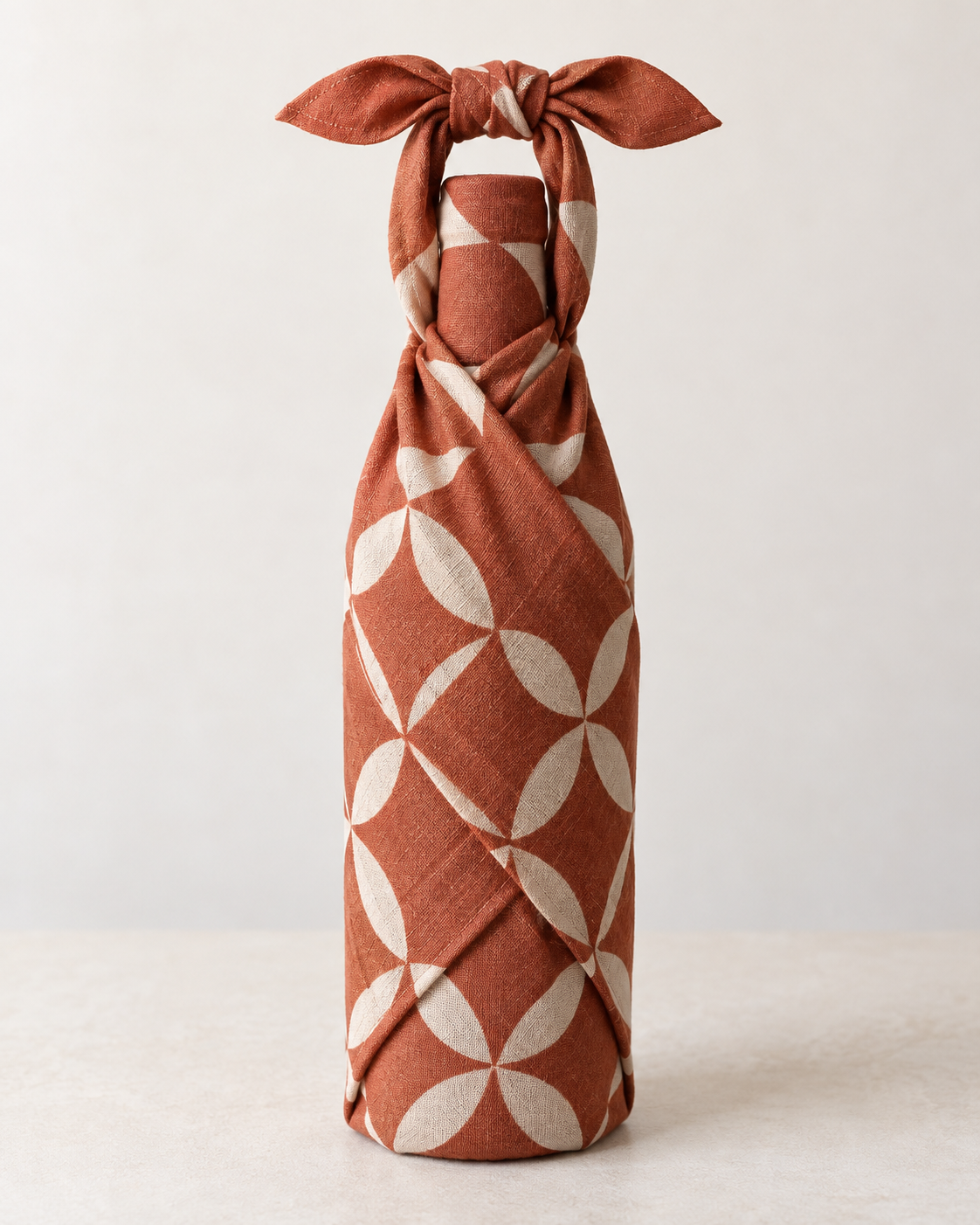 Finished bottle wrapped upright in patterned fabric with a secure knot above the shoulder