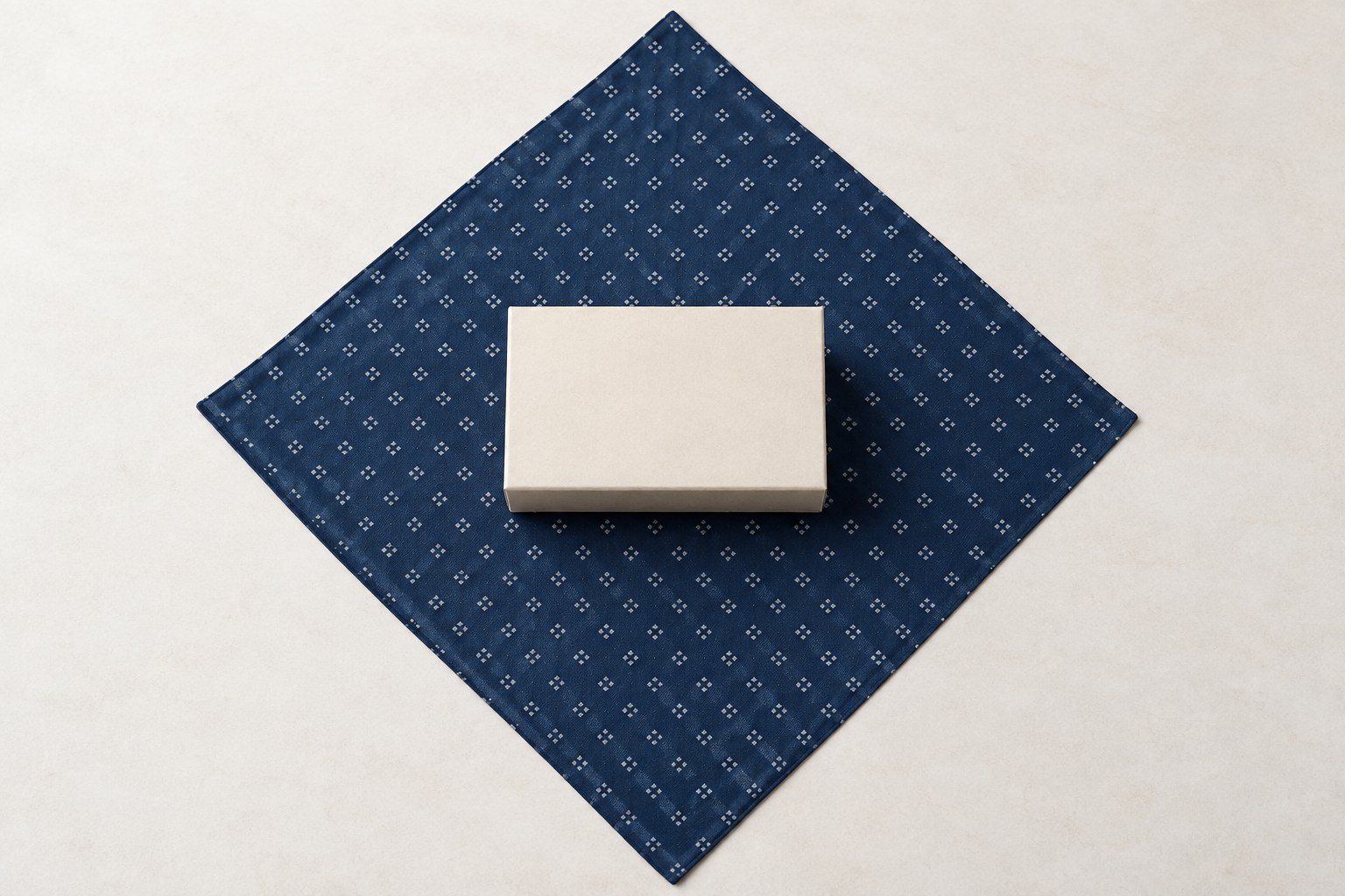Square cloth laid as a diamond with a rectangular gift box centred for a basic furoshiki wrap